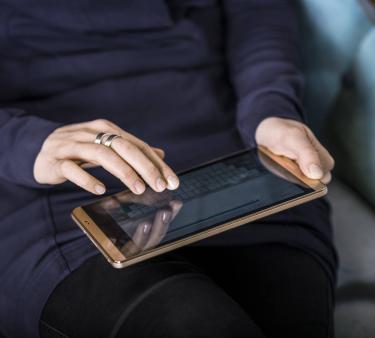 Nainen iPad sylissään naputtelee tabletti