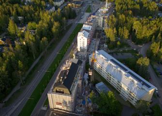 Ilmakuva kerrostaloista metsäisessä maisemassa.