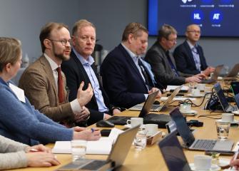 Kokoushuoneessa istuvia henkilöitä keskustelemassa valtion tukemaan asuntotuotantoon liittyvistä teemoista pöydän ääressä, edessään tietokoneita ja muistiinpanovälineitä.