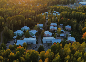 Ilmakuva asuinalueesta, jossa useita muutaman kerroksen kerrostaloja metsäisen alueen keskellä.
