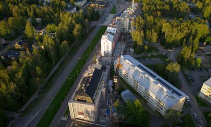Ilmakuva kerrostaloista metsäisessä maisemassa.