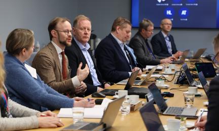 Kokoushuoneessa istuvia henkilöitä keskustelemassa valtion tukemaan asuntotuotantoon liittyvistä teemoista pöydän ääressä, edessään tietokoneita ja muistiinpanovälineitä.