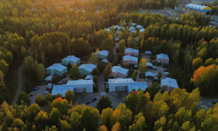 Ilmakuva asuinalueesta, jossa useita muutaman kerroksen kerrostaloja metsäisen alueen keskellä.
