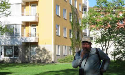 Tietokirjailija Mikko Laaksonen seisoo keltaisen kerrostalon edustalla.